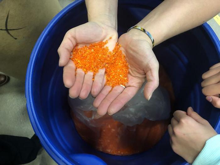 hands hold orange plastic particles